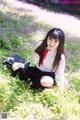 A woman sitting in a field of flowers holding a flower.