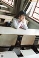 A woman sitting at a desk in a classroom.