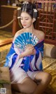 A woman in a blue and white dress holding a fan.