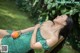 A woman in a green dress laying on a wooden bench.