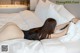 A woman laying on a bed with white sheets and pillows.