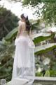 A woman in a white dress standing on a bridge.