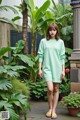 A woman in a green sweater dress standing in a garden.