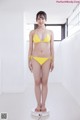 A woman in a yellow bikini standing on a scale.