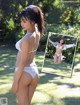 A woman in a white bikini standing in the grass.