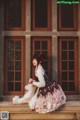 A woman sitting on the steps of a building holding a teddy bear.