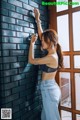 A woman leaning against a brick wall with her hand on the wall.