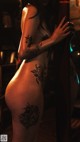 A woman with a tattoo on her back leaning against a pole.