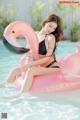 A woman in a black bikini sitting on an inflatable flamingo.