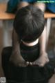 A person sitting on a chair with their hands clasped together.