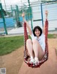 A woman sitting on a swing in a park.