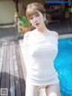 a woman in a white dress standing next to a pool