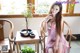 A woman in a pink dress sitting on a wooden chair.