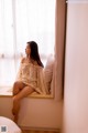 A woman sitting on a window sill looking out the window.