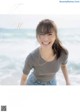 A woman standing on a beach next to the ocean.