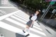 A woman in a school uniform is crossing the street.