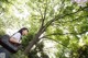 A woman standing in front of a tree with a bag.