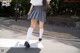 A woman in a skirt and white socks crossing the street.