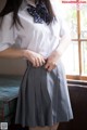 A woman in a white shirt and gray skirt posing for a picture.