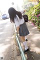 A woman in a school uniform leaning against a railing.