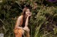 A woman in an orange polka dot dress sitting in a field of flowers.