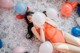 A woman laying on the floor surrounded by balloons.