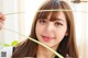 A woman holding a plant in front of her face.