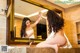 A naked woman sitting in front of a mirror in a bathroom.